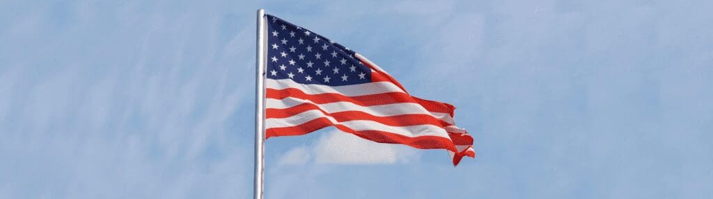 The American flag waves against a clear blue sky.